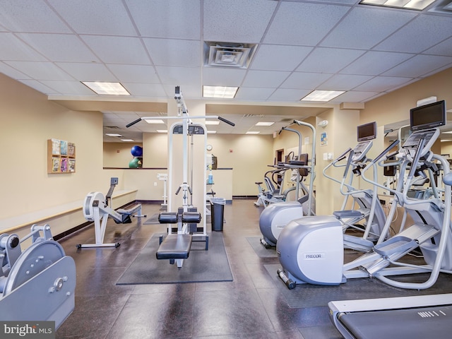 workout area with a drop ceiling, visible vents, and baseboards