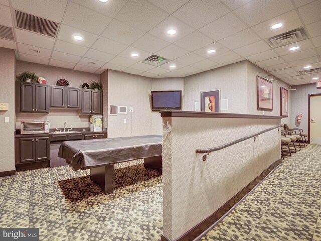 interior space with billiards, dark brown cabinets, dark carpet, a paneled ceiling, and sink