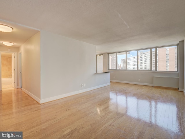 empty room featuring a textured ceiling and light hardwood / wood-style flooring