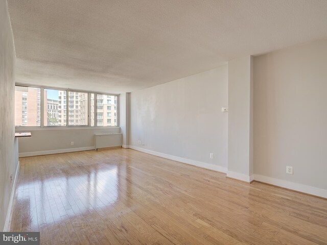 unfurnished room featuring radiator, a textured ceiling, and light hardwood / wood-style flooring