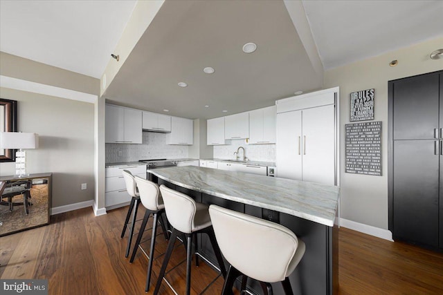 kitchen featuring white cabinets, sink, dark hardwood / wood-style floors, decorative backsplash, and a kitchen island