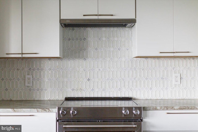 kitchen featuring decorative backsplash, stainless steel stove, and white cabinetry