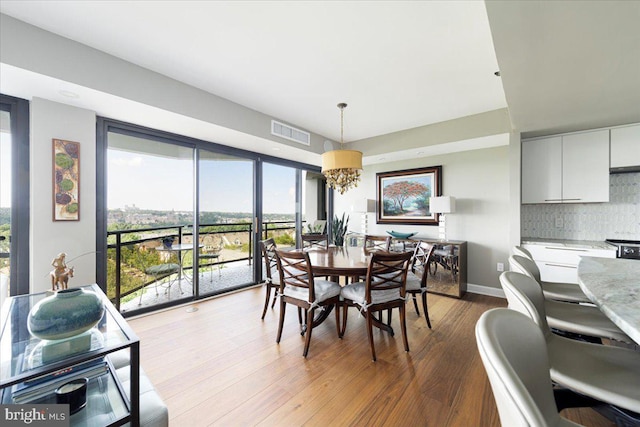 dining space with hardwood / wood-style flooring and a notable chandelier