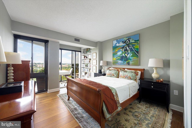 bedroom featuring access to exterior, a textured ceiling, and light wood-type flooring