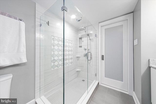 bathroom with toilet, tile patterned floors, and a shower with shower door