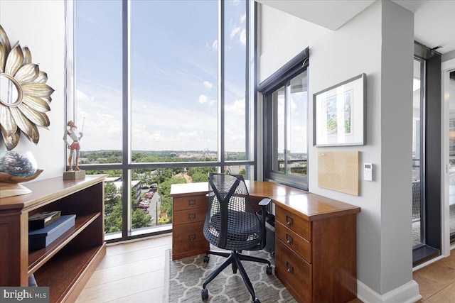 office space featuring floor to ceiling windows, plenty of natural light, and light hardwood / wood-style floors