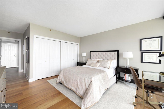 bedroom featuring wood-type flooring, a textured ceiling, and two closets