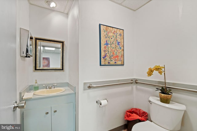 bathroom featuring toilet, a paneled ceiling, and vanity