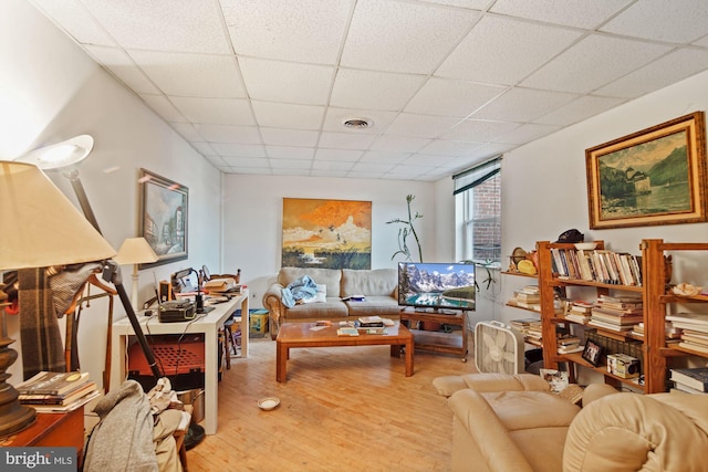 living room with light hardwood / wood-style flooring and a paneled ceiling