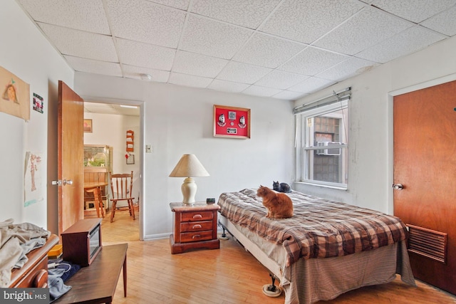 bedroom featuring a paneled ceiling and light hardwood / wood-style floors