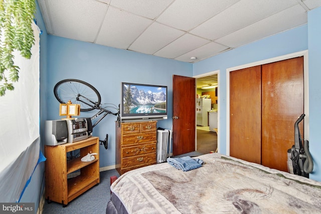 carpeted bedroom with a paneled ceiling, white fridge, and a closet