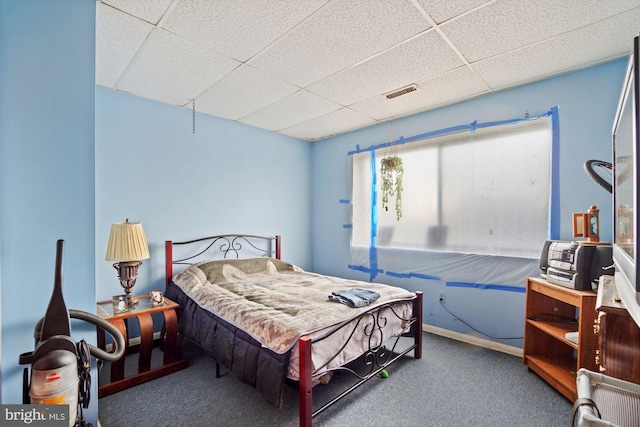 carpeted bedroom featuring baseboards, visible vents, and a drop ceiling