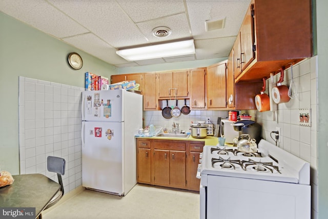 kitchen with a paneled ceiling, tile walls, light tile patterned floors, and white appliances