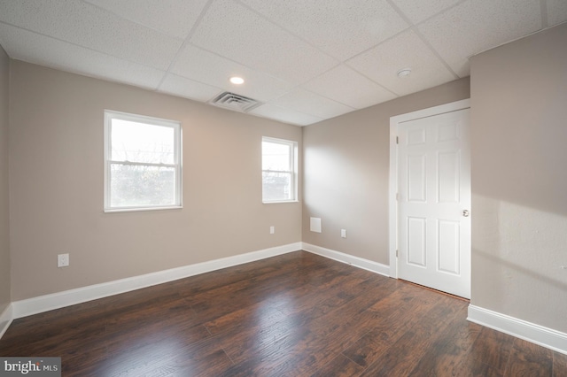 unfurnished room with dark hardwood / wood-style floors and a drop ceiling