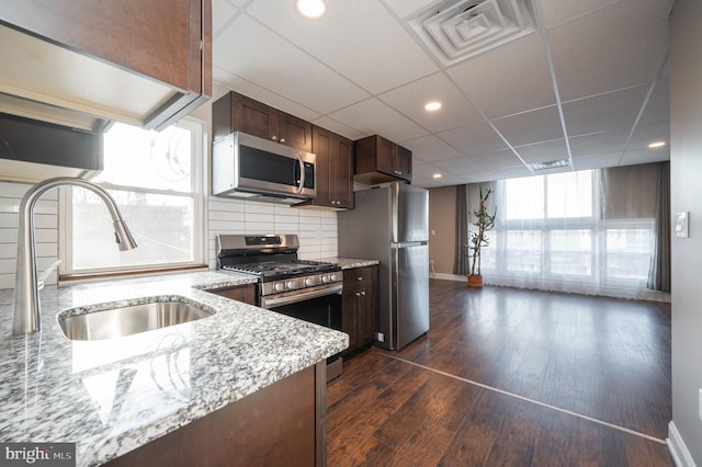 kitchen with stainless steel appliances, sink, dark hardwood / wood-style floors, a drop ceiling, and decorative backsplash