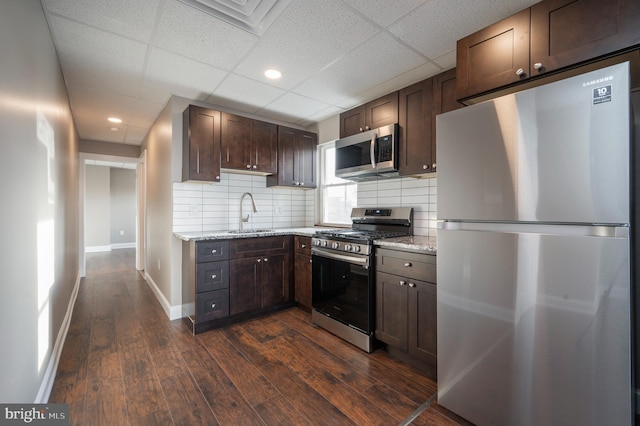 kitchen with backsplash, dark hardwood / wood-style floors, appliances with stainless steel finishes, and a drop ceiling