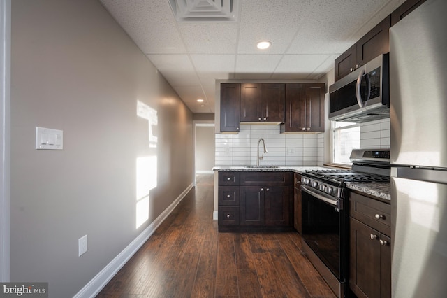 kitchen with a drop ceiling, sink, decorative backsplash, dark hardwood / wood-style floors, and appliances with stainless steel finishes