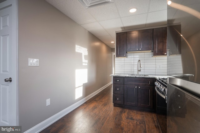 kitchen with dark hardwood / wood-style floors, dark brown cabinets, sink, decorative backsplash, and a paneled ceiling