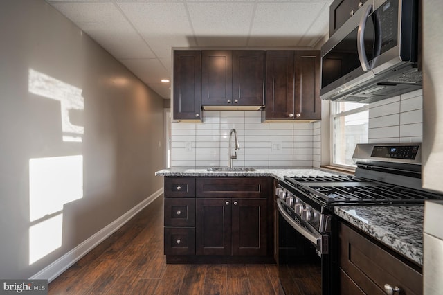 kitchen featuring tasteful backsplash, dark brown cabinets, sink, dark wood-type flooring, and appliances with stainless steel finishes