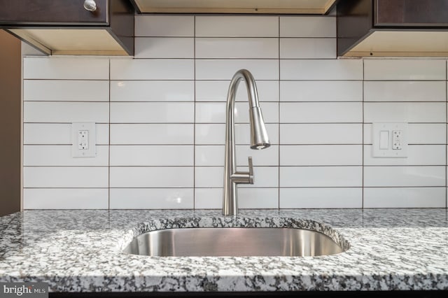 kitchen featuring light stone counters, a sink, and dark brown cabinets