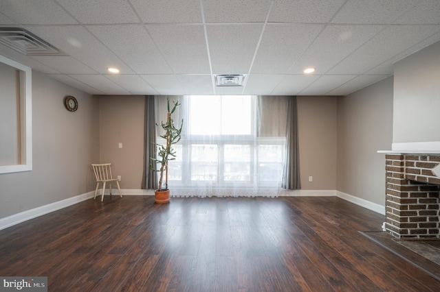 unfurnished living room featuring wood-type flooring and a paneled ceiling