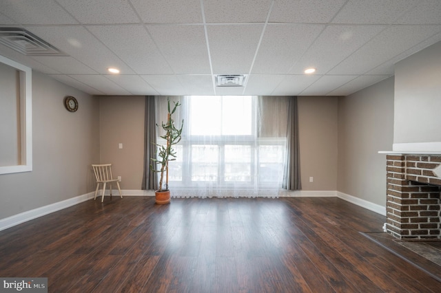 unfurnished living room with dark wood-style floors, a brick fireplace, and visible vents