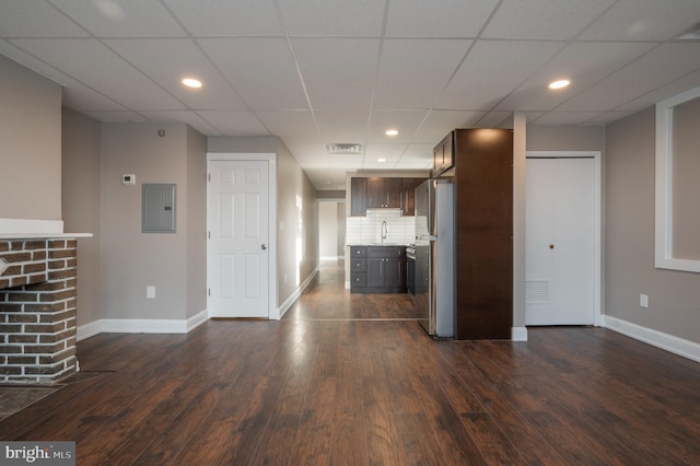 unfurnished living room featuring a paneled ceiling and dark hardwood / wood-style flooring