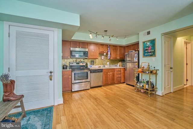 kitchen with backsplash, sink, light hardwood / wood-style flooring, and stainless steel appliances