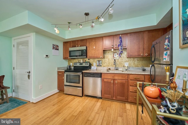 kitchen with light wood-type flooring, backsplash, sink, and stainless steel appliances