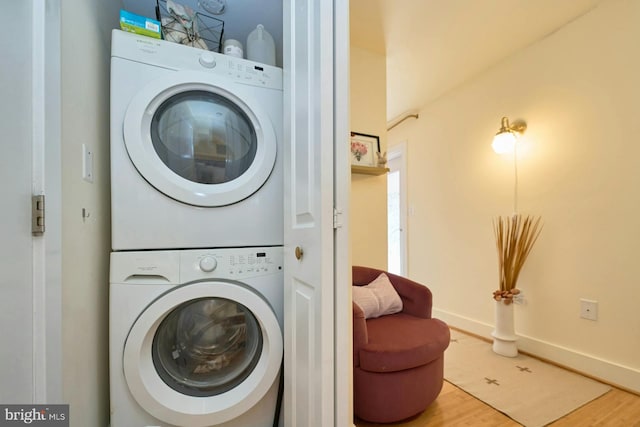 clothes washing area featuring wood-type flooring and stacked washer and dryer