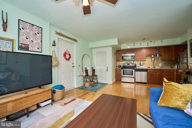 living room featuring ceiling fan, light wood-type flooring, and sink