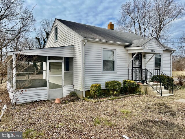 view of front of property featuring a front lawn and a sunroom