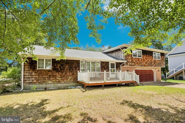 rear view of property with a wooden deck, a garage, and a yard