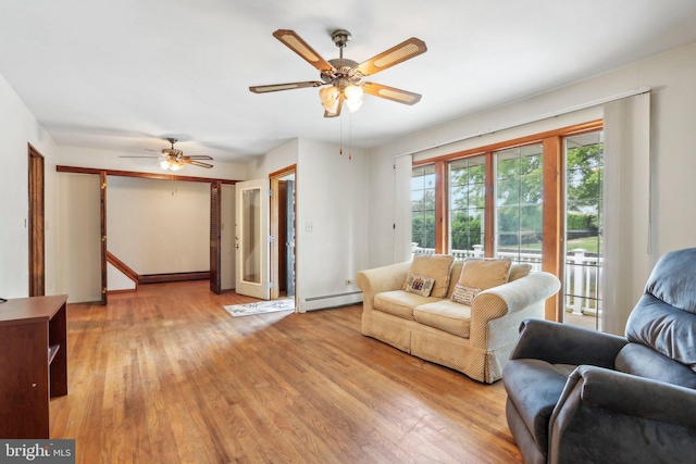 living room featuring baseboard heating, ceiling fan, and light hardwood / wood-style floors