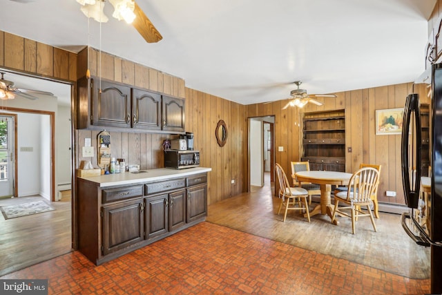 kitchen with baseboard heating, ceiling fan, wooden walls, and dark hardwood / wood-style flooring