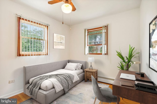 bedroom featuring light hardwood / wood-style flooring, a baseboard radiator, and ceiling fan