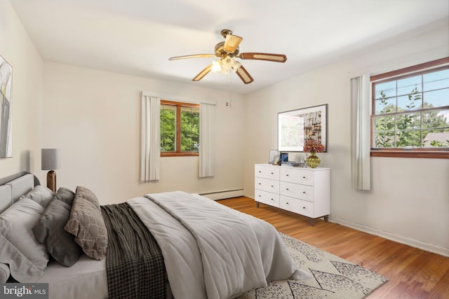 bedroom with light wood-type flooring, ceiling fan, and baseboard heating