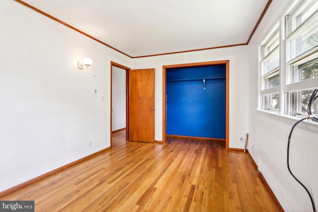 unfurnished bedroom featuring a closet, ornamental molding, and light hardwood / wood-style flooring