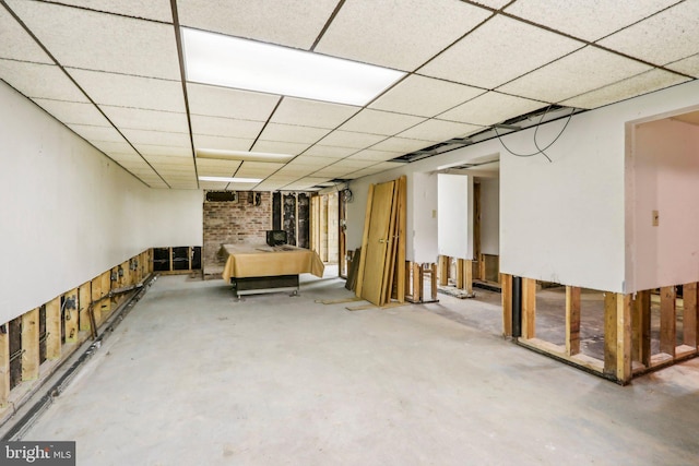 basement with a wood stove and a paneled ceiling