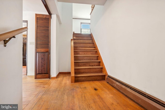 stairs with hardwood / wood-style floors and a baseboard radiator