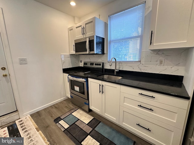 kitchen with backsplash, white cabinets, sink, dark hardwood / wood-style floors, and stainless steel appliances