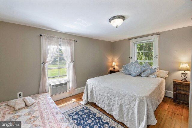 bedroom featuring cooling unit, multiple windows, and light hardwood / wood-style floors