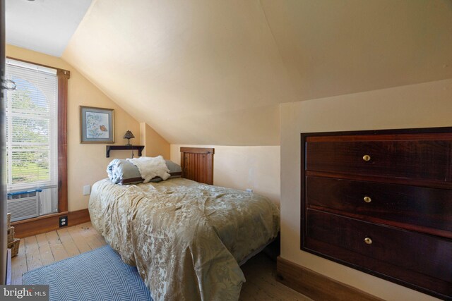 bedroom featuring cooling unit, hardwood / wood-style flooring, and vaulted ceiling