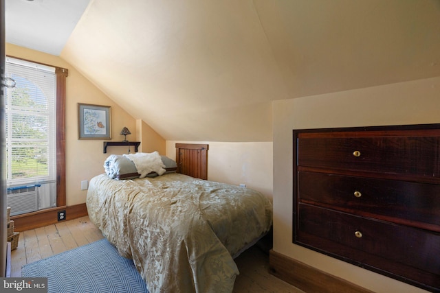 bedroom with cooling unit, vaulted ceiling, and wood finished floors