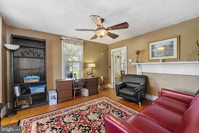 living room with light wood finished floors, ceiling fan, and baseboards