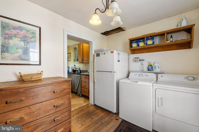 laundry room featuring wood-type flooring, an inviting chandelier, and independent washer and dryer