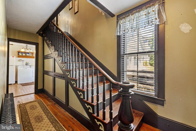 stairs featuring washing machine and dryer, beamed ceiling, and hardwood / wood-style floors