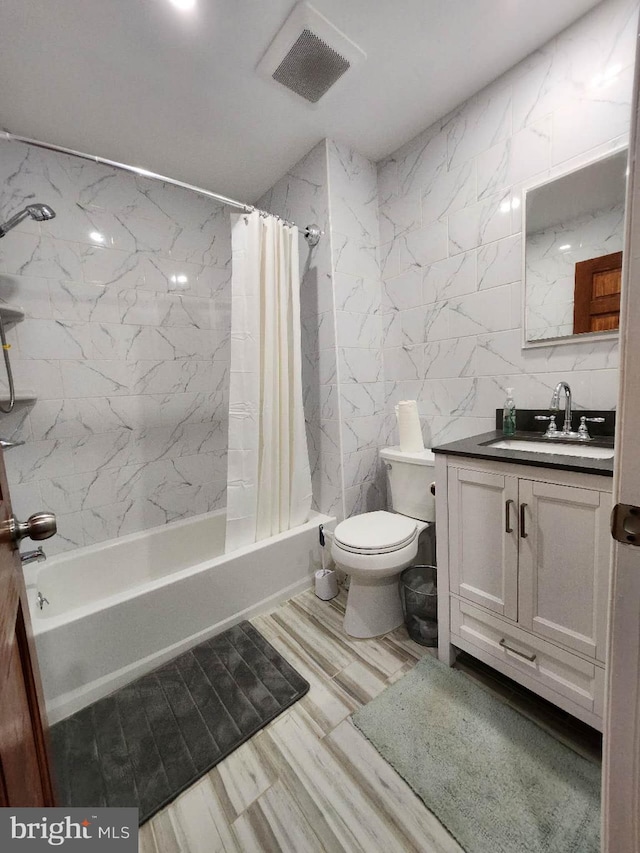 full bathroom with vanity, tile walls, toilet, and shower / bath combo