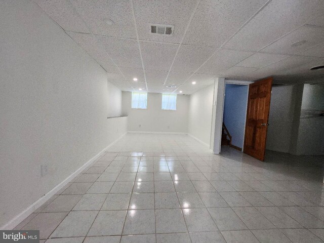 below grade area featuring baseboards, visible vents, a drop ceiling, light tile patterned flooring, and recessed lighting