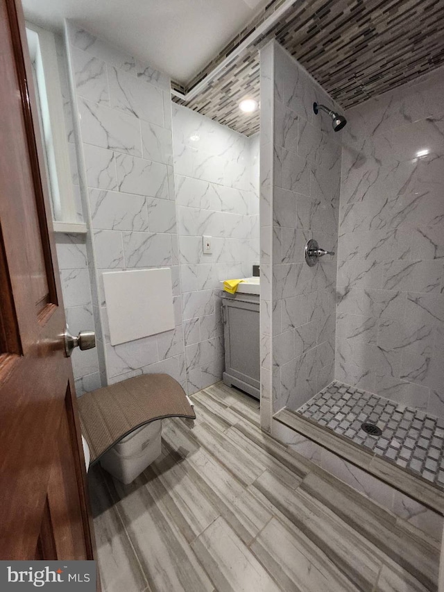 bathroom featuring vanity, tile walls, and tiled shower